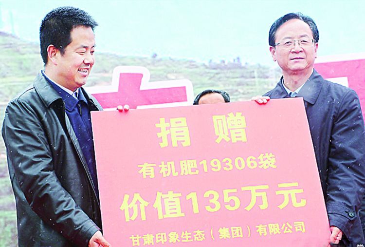 公司董事长闫鹏飞（左）为贫困群众捐赠有机肥
